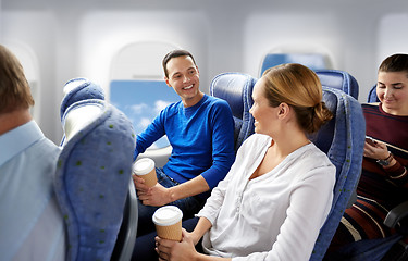 Image showing happy passengers with coffee talking in plane