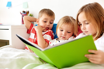 Image showing little kids reading book in bed at home