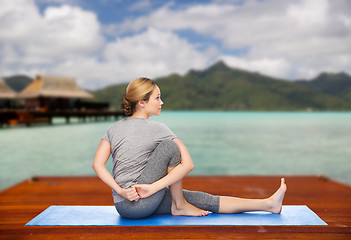 Image showing woman making yoga in twist pose on mat outdoors