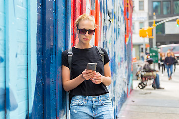 Image showing Woman using smartphone against colorful graffiti wall in New York city, USA.
