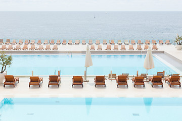 Image showing Luxury swimming pool with wooden deck chairs.