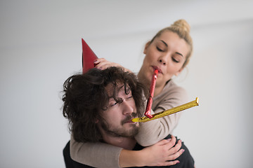 Image showing couple in party hats blowing in whistle