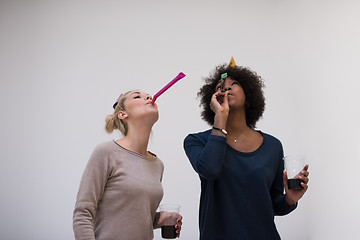 Image showing smiling women in party caps blowing to whistles