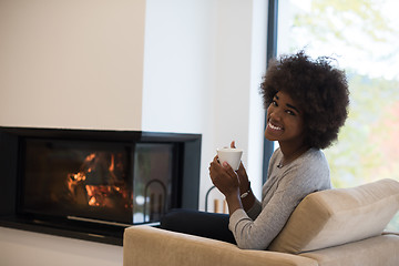 Image showing black woman drinking coffee in front of fireplace