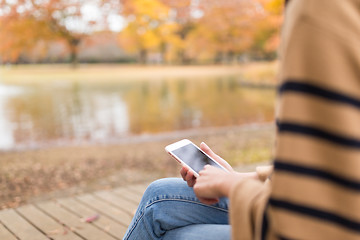 Image showing Woman using cellphone in the park in autumn season