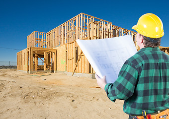 Image showing Contractor with Plans and Hard Hat Looking At New House Framing 