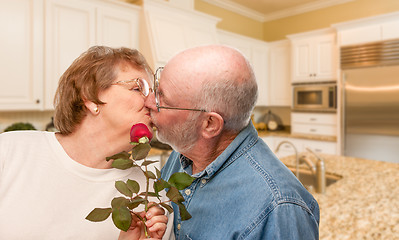 Image showing Happy Senior Adult Man Giving Red Rose to His Wife Inside Kitche