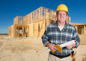 Image showing Contractor with Plans and Hard Hat In Front of New House Framing