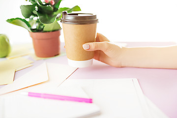 Image showing The female hands holding coffee on trendy pink desk.