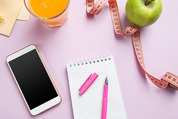 Image showing Top view of green apple, measuring tape, mobile phone, pen and open notebook. Fitness Concept.