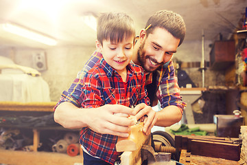 Image showing father and son with plane shaving wood at workshop