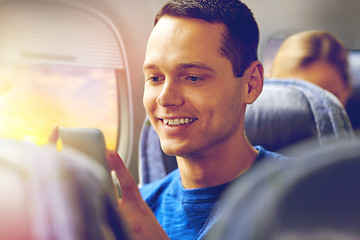 Image showing happy man sitting in plane with smartphone