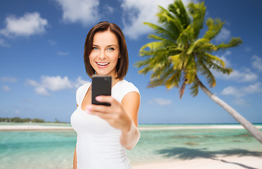 Image showing woman taking selfie by smartphone on beach