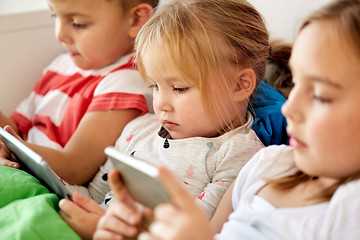 Image showing kids with tablet pc and smartphone in bed at home