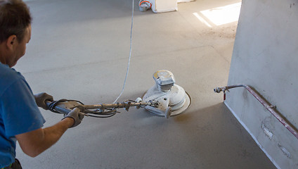 Image showing Laborer polishing sand and cement screed floor.