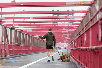 Image showing Unrecognizable sporty recreational male jogger with his dog on a leash at Williamsburg bridgein New York CIty, USA