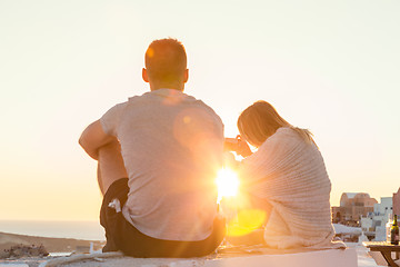 Image showing Couple watching sunrise and taking vacation photos at Santorini island, Greece.