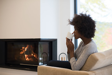 Image showing black woman drinking coffee in front of fireplace