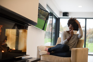 Image showing black woman drinking coffee in front of fireplace