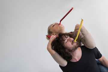 Image showing couple in party hats blowing in whistle