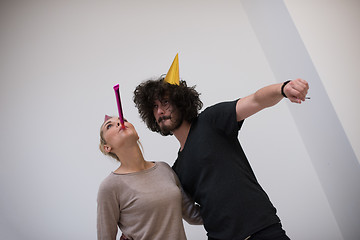 Image showing couple in party hats blowing in whistle