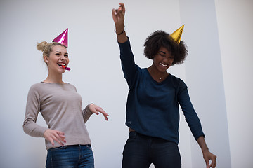 Image showing smiling women in party caps blowing to whistles