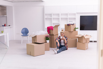 Image showing woman with many cardboard boxes sitting on floor