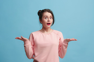 Image showing Portrait of dissatisfied young woman over blue. Beautiful woman looking suprised