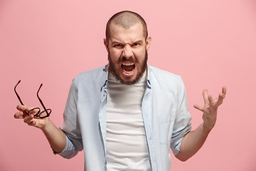 Image showing The young emotional angry man screaming on pink studio background