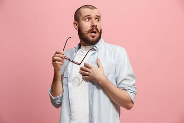 Image showing Let me think. Doubtful pensive man with thoughtful expression making choice against pink background