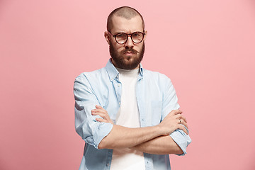 Image showing The serious business man standing and looking at camera against pink background.