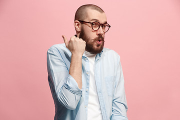 Image showing The young man whispering a secret behind her hand over pink background