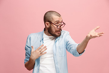 Image showing Beautiful male half-length portrait isolated on pink studio backgroud. The young emotional surprised man