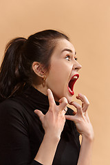 Image showing The young emotional angry woman screaming on pastel studio background