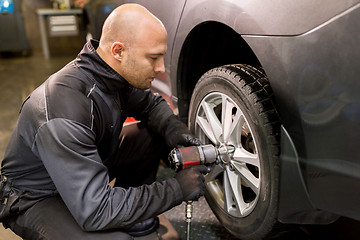 Image showing auto mechanic with screwdriver changing car tire