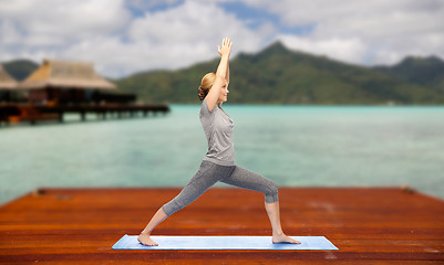 Image showing woman making yoga warrior pose on mat outdoors