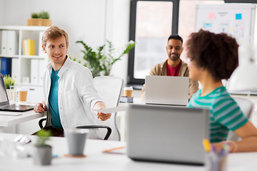 Image showing happy creative workers with laptops at office