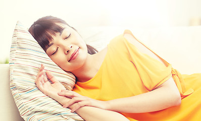 Image showing happy asian teenage girl sleeping on sofa at home