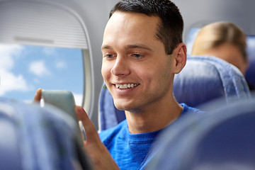 Image showing happy man sitting in plane with smartphone