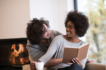 Image showing multiethnic couple hugging in front of fireplace