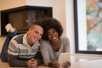 Image showing multiethnic couple using tablet computer on the floor