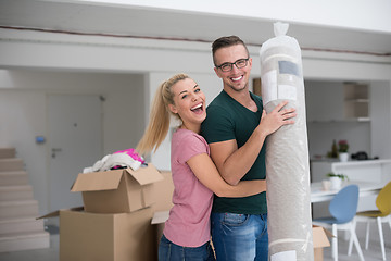 Image showing couple carrying a carpet moving in to new home