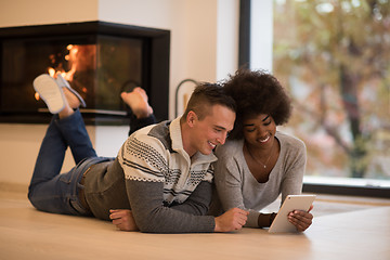 Image showing multiethnic couple using tablet computer on the floor