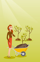 Image showing Woman pushing wheelbarrow with plant.