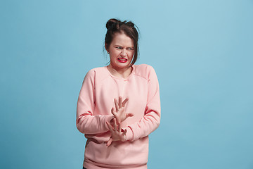 Image showing Young woman with disgusted expression repulsing something, isolated on the blue