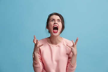 Image showing The young emotional angry woman screaming on blue studio background