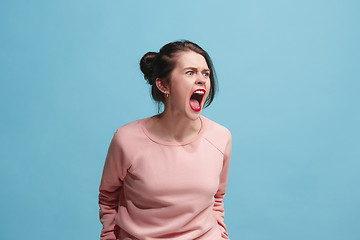 Image showing The young emotional angry woman screaming on blue studio background