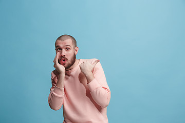 Image showing The young man whispering a secret behind her hand over blue background