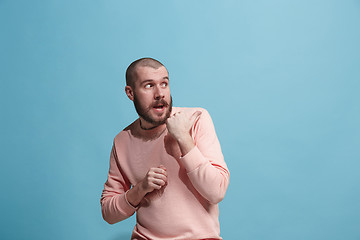 Image showing The young man whispering a secret behind her hand over blue background