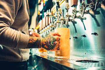 Image showing Hand of bartender pouring a large lager beer in tap.